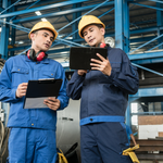 Ingeniero llevando el control en tiempo real de sus operaciones con una tablet en la mano y un compañero a su lado.